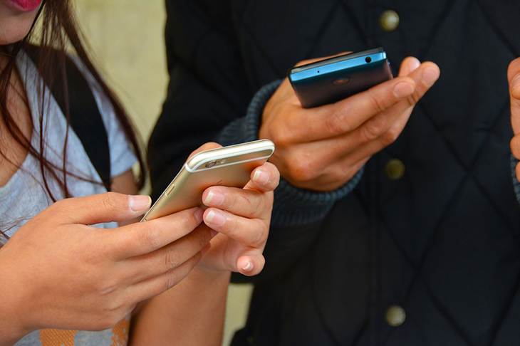 Två personer som håller i mobiltelefoner.