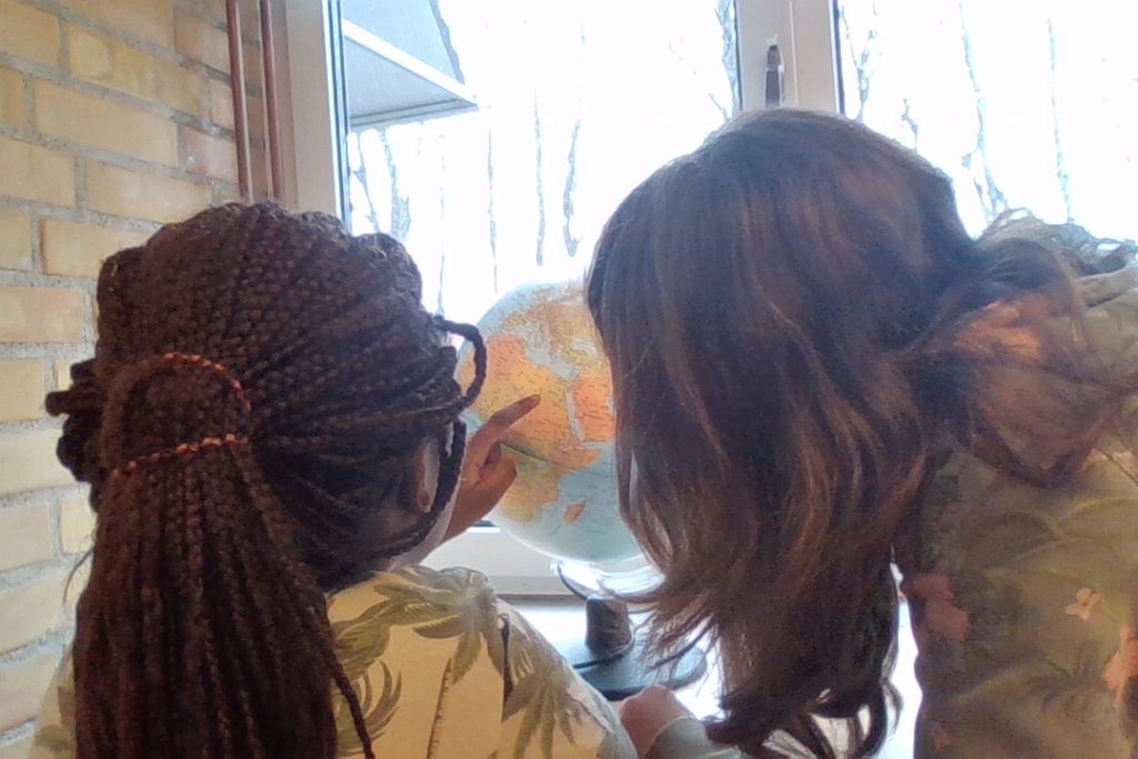 Maeva och Munise som tittar och pekar på en jordglob.