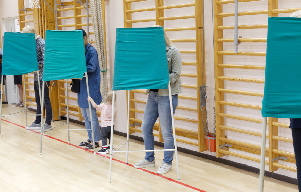 Bild på människor som röstar bakom skärmar.